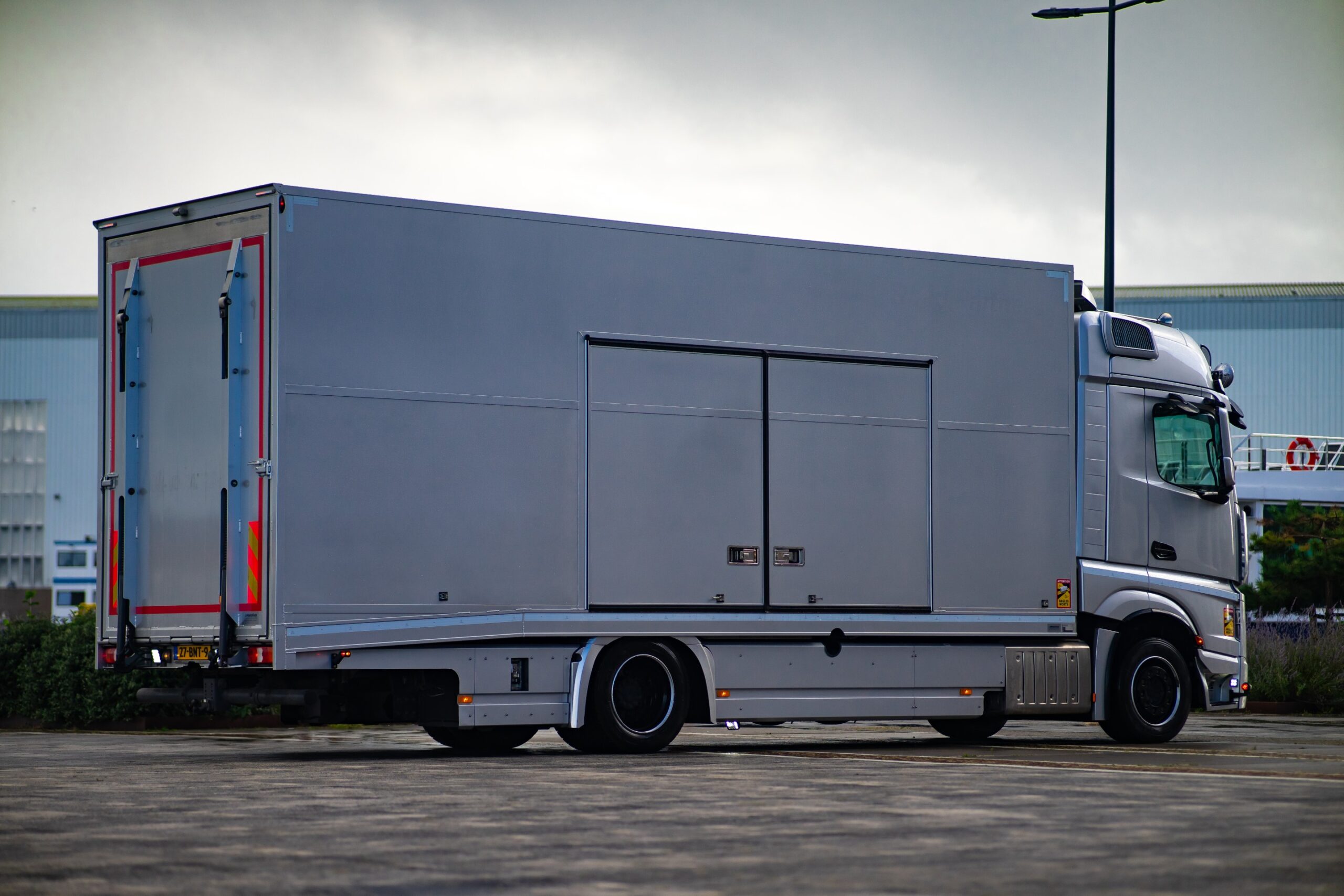 Silberner geschlossener Autotransporter mit doppelten Seitentüren, abgestellt auf einem Betriebsgelände