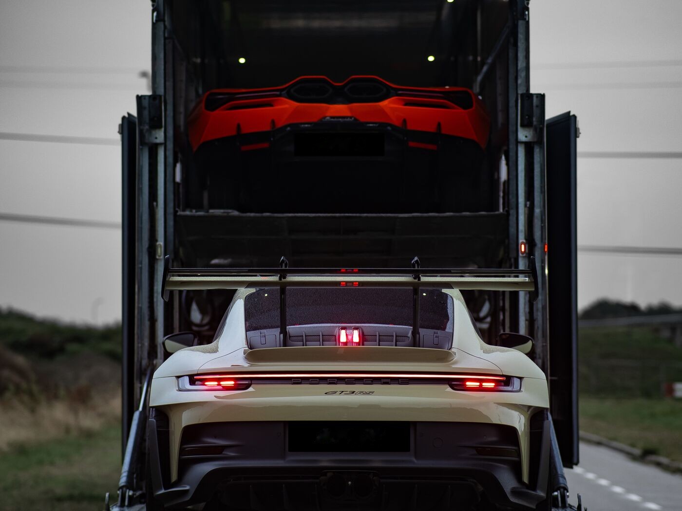 Rückansicht eines geschlossenen Doppelstock-Transporters mit einem Sportwagen auf jedem Deck