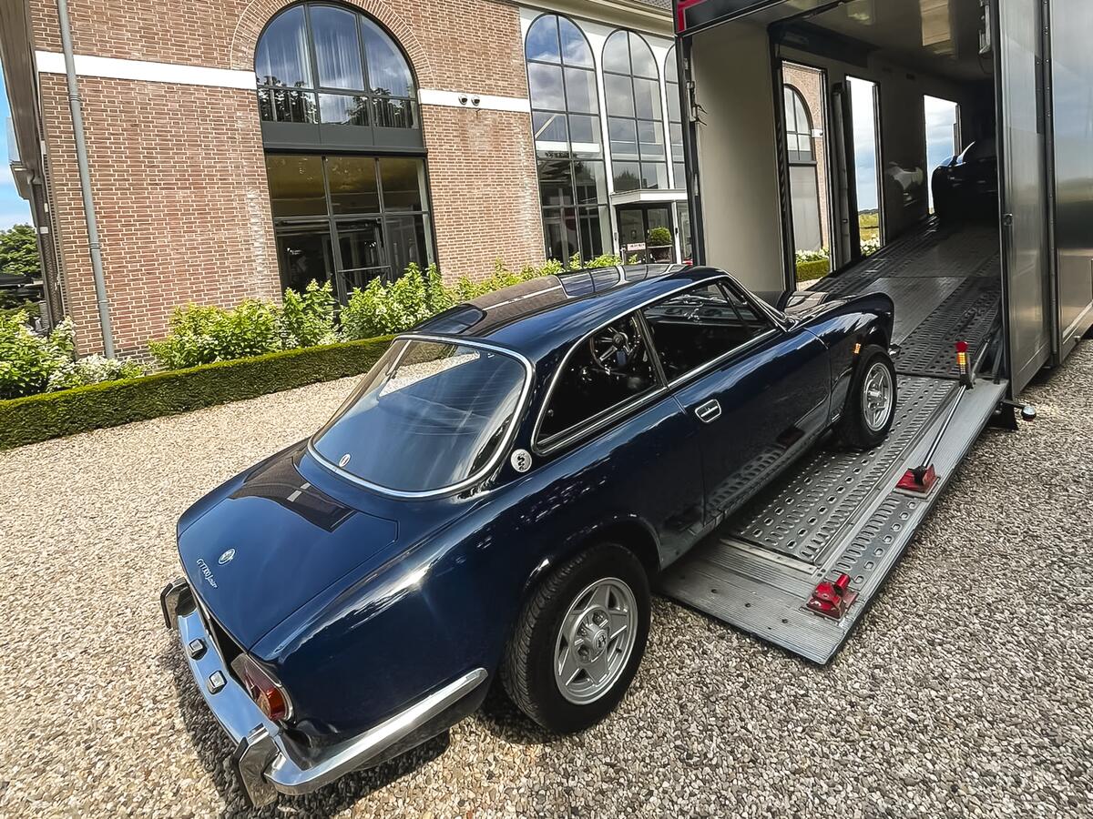 Klassischer Alfa Romeo an der Laderampe eines geschlossenen Anhängers vor einer Villa