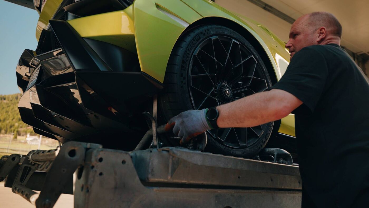 Sportwagen wird mit Zurrgurten über den Rädern im Trailer gesichert